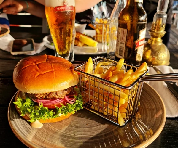 En tallrik med en hamburgare, pommes frites och ett glas öl på Oliver Twist